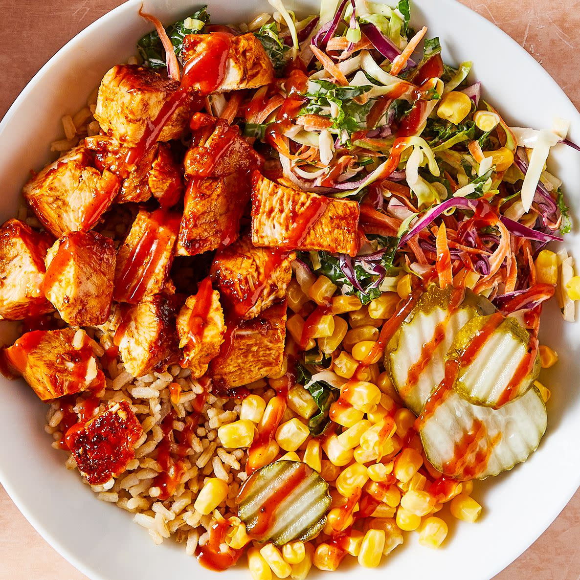 bbq chicken in a bowl with corn, pickles, and slaw