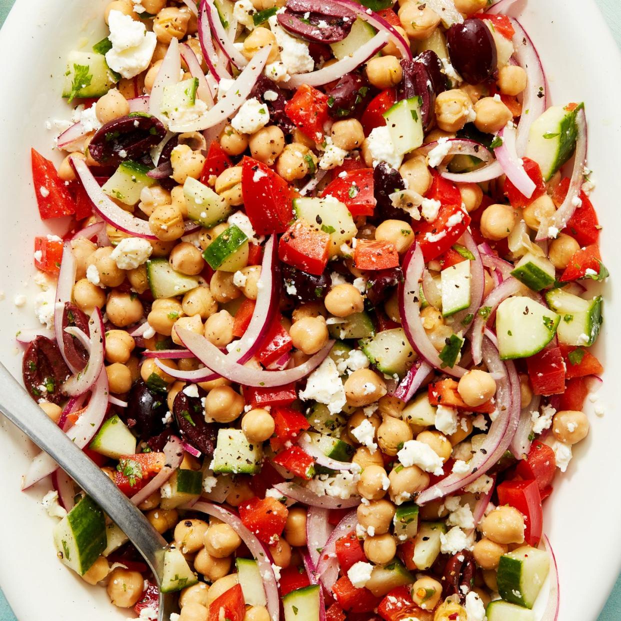 peas with olives, feta, cucumbers, sliced ​​red onion, and red pepper on a white platter.