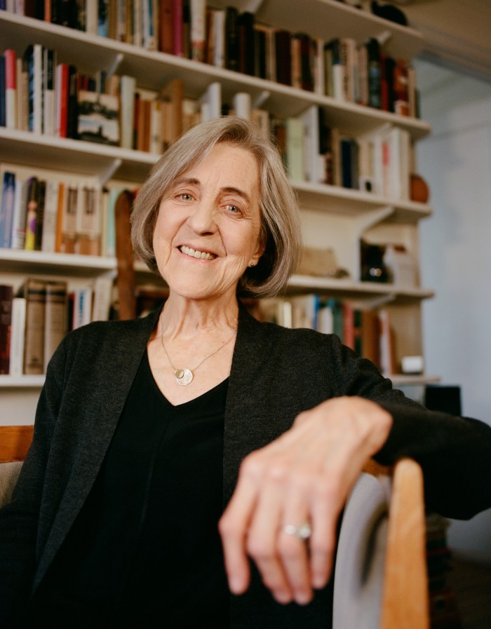 Rita Charon sits in a chair in front of a wall full of books on shelves